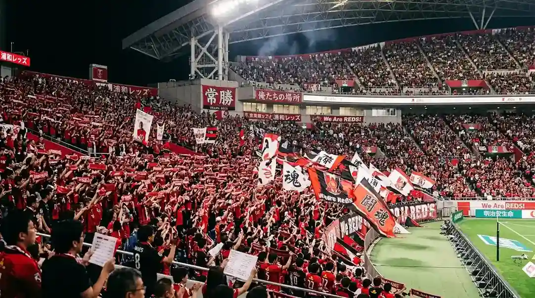 Gradas de un estadio de la J.League repletas de aficionados con banderas y bufandas de colores durante un partido